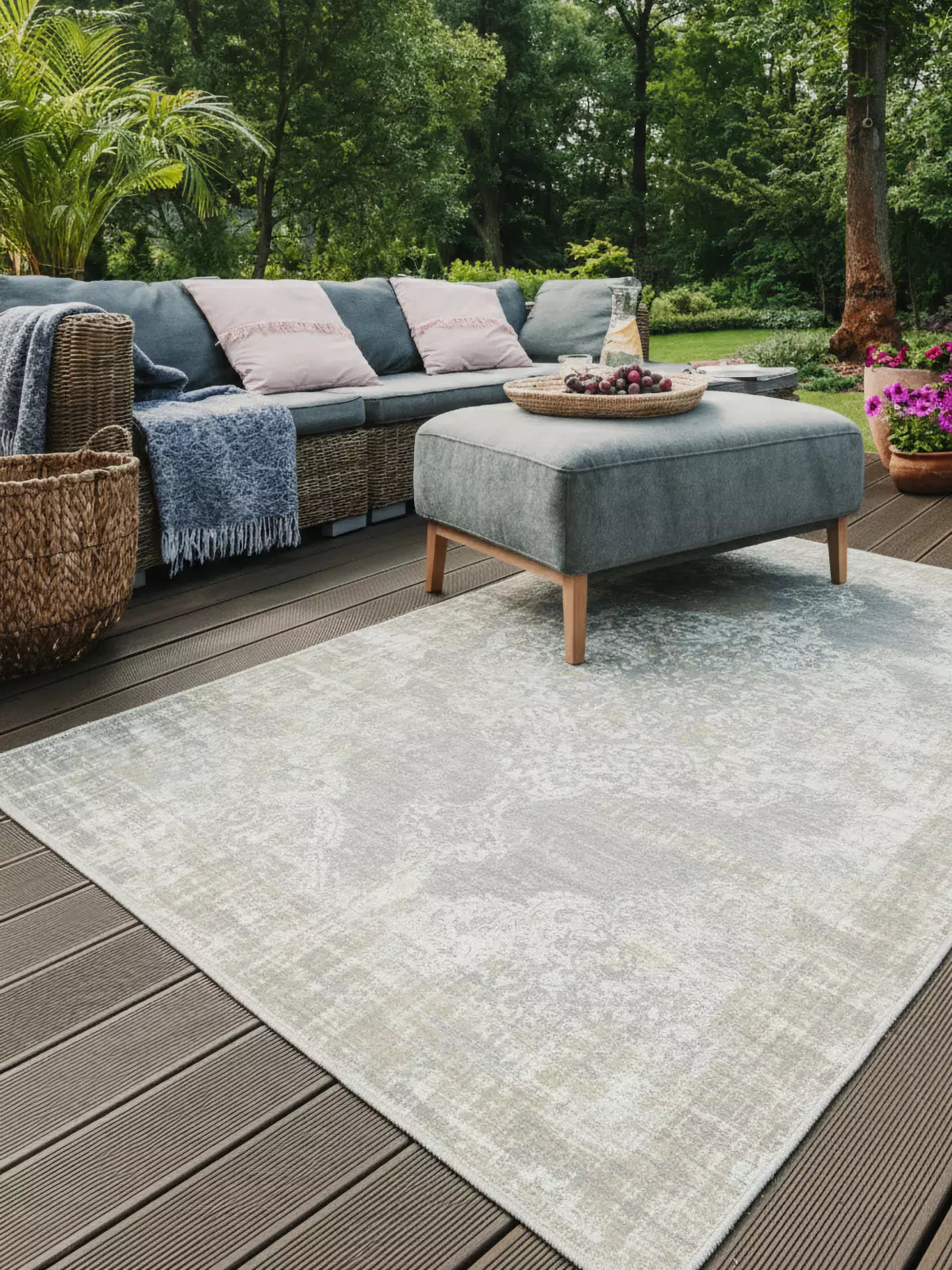 Young woman reading a book while lying on a blue and red plaid outdoor rug in a grassy field, showcasing a comfortable and stylish outdoor living experience.
